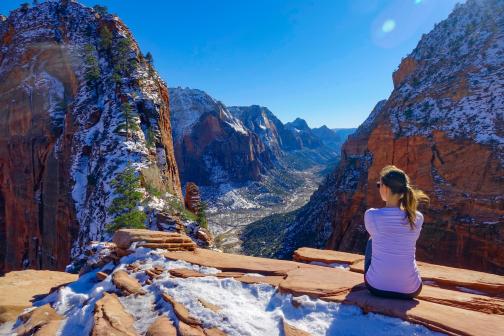 Woman sitting on a cliff overlooking a valley in Utah